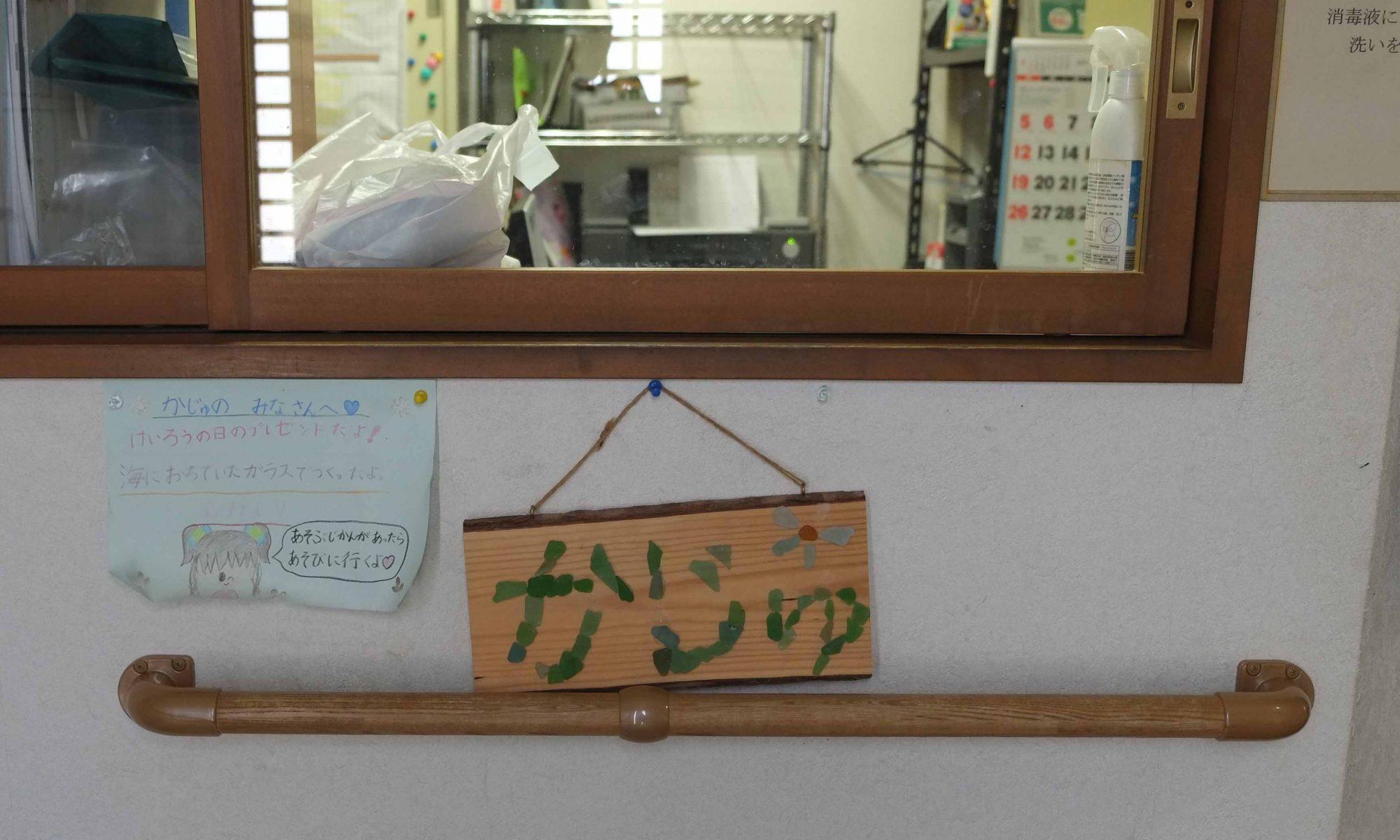 施設内の掲示板。手書きメッセージと木製の看板が壁に掛かっている。